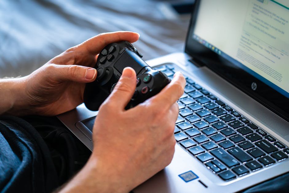 Person holds a gaming controller while interacting with a laptop, emphasizing modern gaming technology. — Photo by Castorly Stock on Pexels