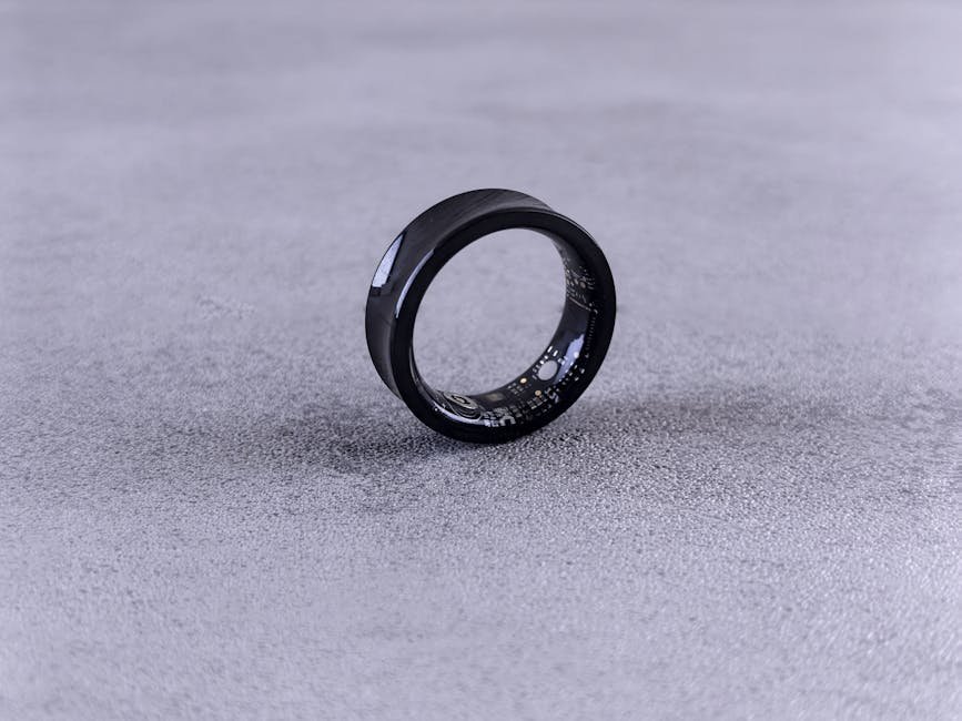 A modern black smart ring with visible circuitry resting on a textured concrete surface. — Photo by Andrey Matveev on Pexels